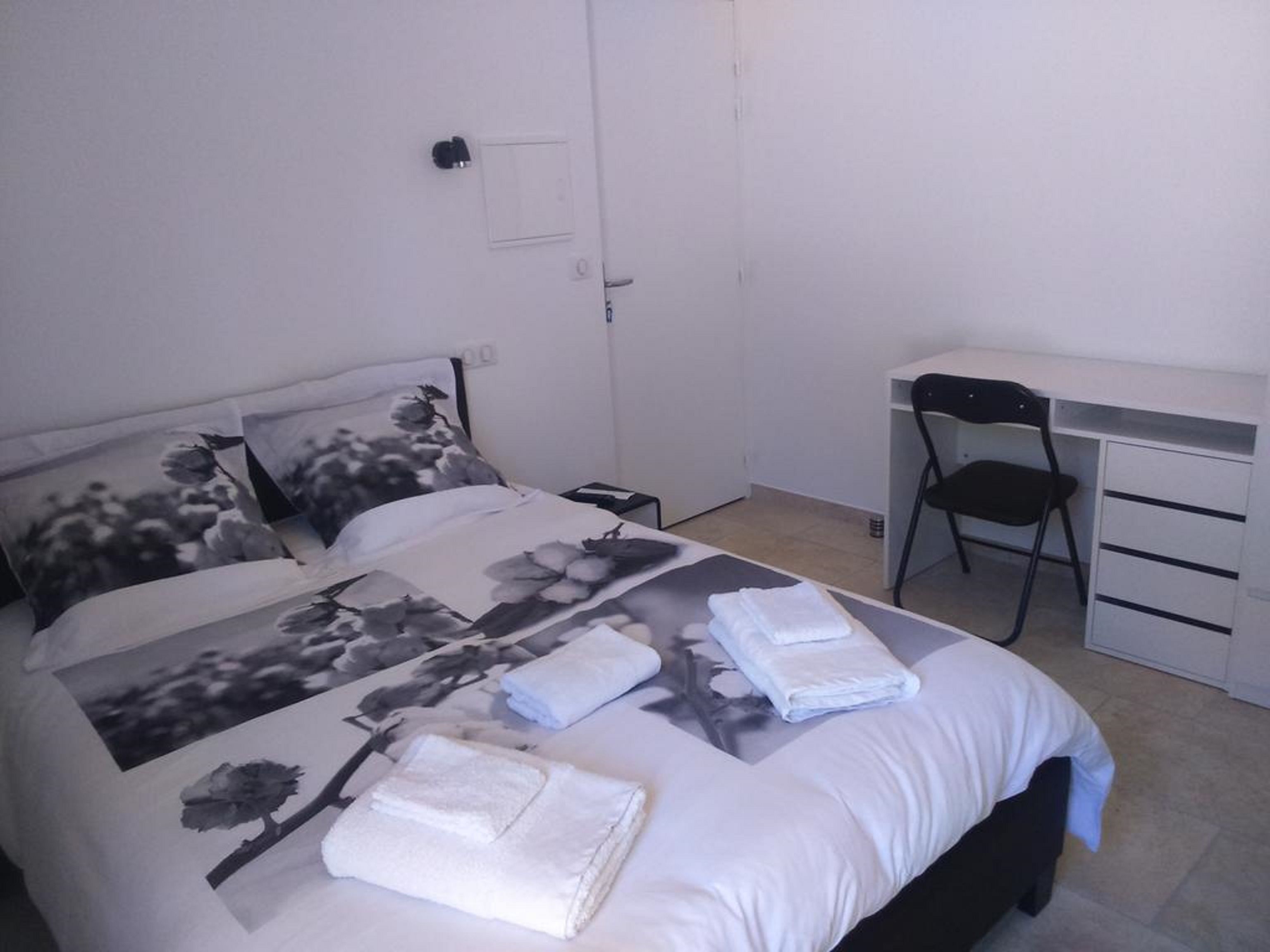 Un dormitorio con cama, escritorio y silla.