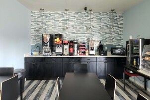 Una cocina moderna con salpicadero a rayas, armarios negros y una isla central con microondas y cafeteras.