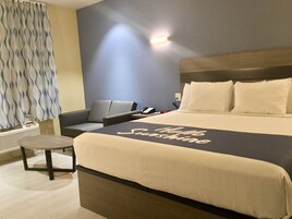 Habitación de hotel con una cama grande, una mesita de noche, una silla, un escritorio y un teléfono en la pared.