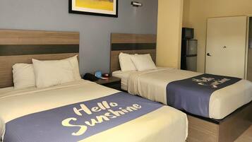 Two twin beds with 'Hello Sunshine' blankets, a clock, a TV on a cabinet, and a door to the right.