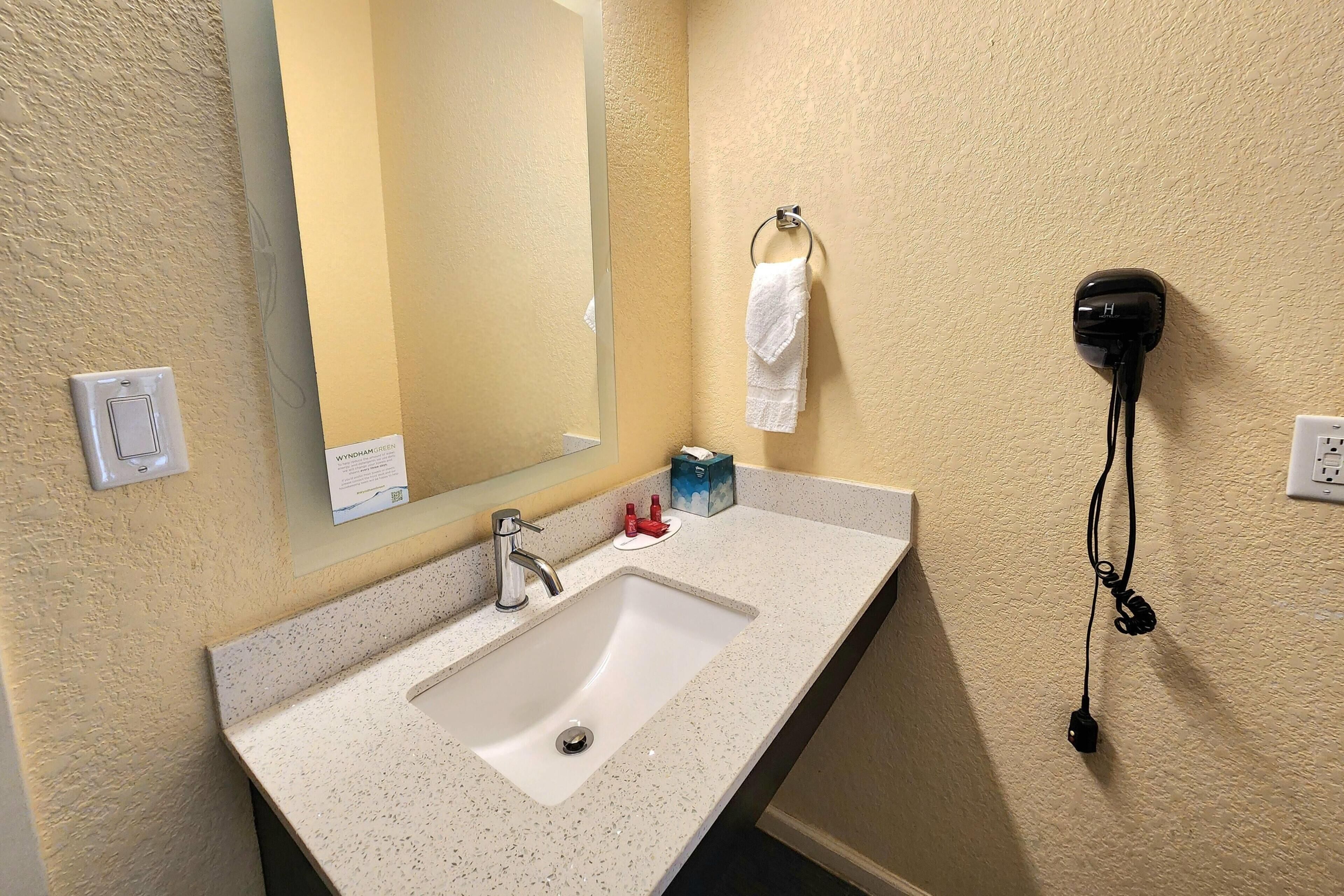 A bathroom with a sink, mirror, towel rack, and hair dryer.