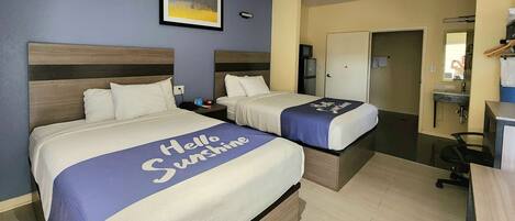 A hotel room with two beds, a desk, a chair, a mirror, and a door.