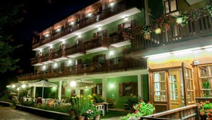 Un hotel de varios pisos con mesas al aire libre y una zona de recepción.
