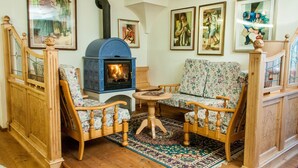 Una habitación acogedora con una cama de madera, un sofá floral y un estufa de leña azul.