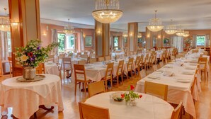Un restaurante con mesas redondas, manteles blancos y sillas de madera.
