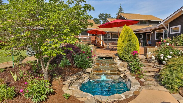 A backyard with a stone fountain, a small pool, and a wooden deck. - Brookside Bed & Breakfast (Hood River)