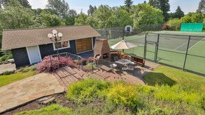 A tennis court with a fence, a barbecue area, and a patio with outdoor furniture. - Brookside Bed & Breakfast (Hood River)