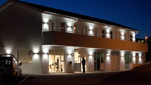 Hotel de dues plantes amb finestres il·luminades i una persona al vestíbul.