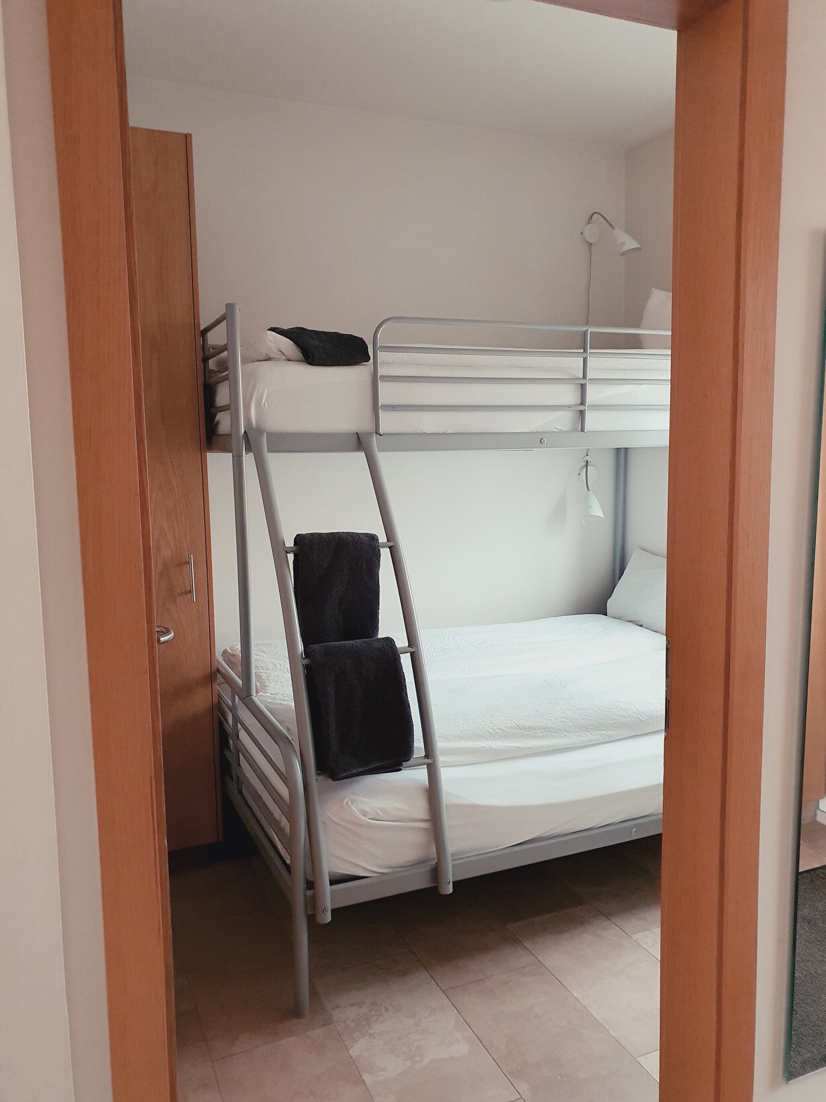 A bunk bed room with a ladder, a small desk, and a door.