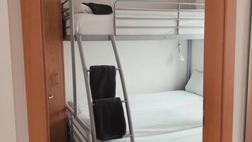 A bunk bed room with a ladder, a small desk, and a door.
