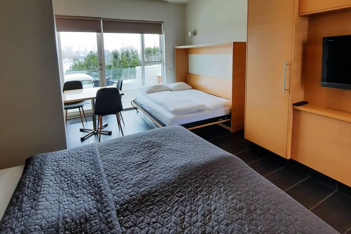 A modern hotel room with a large bed, a desk, and a TV.