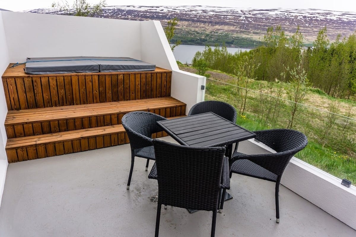 A balcony with a wooden bench, a table, and four chairs.