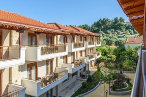 Ein mehrstöckiges Hotel mit Balkonen, einem Innenhof und Blick auf eine hügelige Landschaft.
