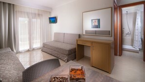 Une chambre d’hôtel avec un lit, un bureau, une télévision, une douche et une fenêtre avec des rideaux.