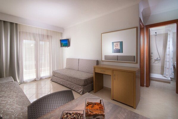 Une chambre d’hôtel avec un lit, un bureau, une télévision, une douche et une fenêtre avec des rideaux.