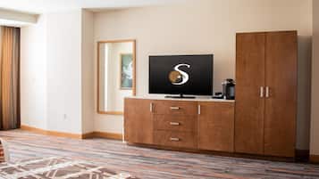 Hotellihuone, jossa on suuri vaatekaappi, litteänäyttöinen televisio, kahvinkeitin ja kuviollinen matto.