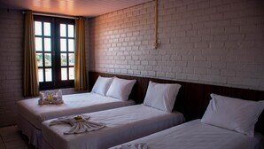 Une chambre d’hôtel avec deux lits, du linge de lit blanc et des serviettes disposées sur chaque lit.