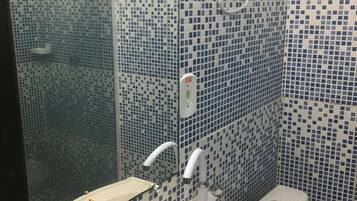 A bathroom with a sink, mirror, and toilet. The walls are tiled with a blue mosaic pattern.