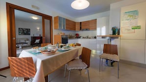 A dining area with a table set for four, a kitchen in the background, and a map on the wall. - B&B La Stradella (Ostuni)