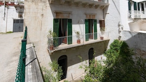 A white building with green shutters and balconies, a small courtyard, and a green fence. - B&B La Stradella (Ostuni)