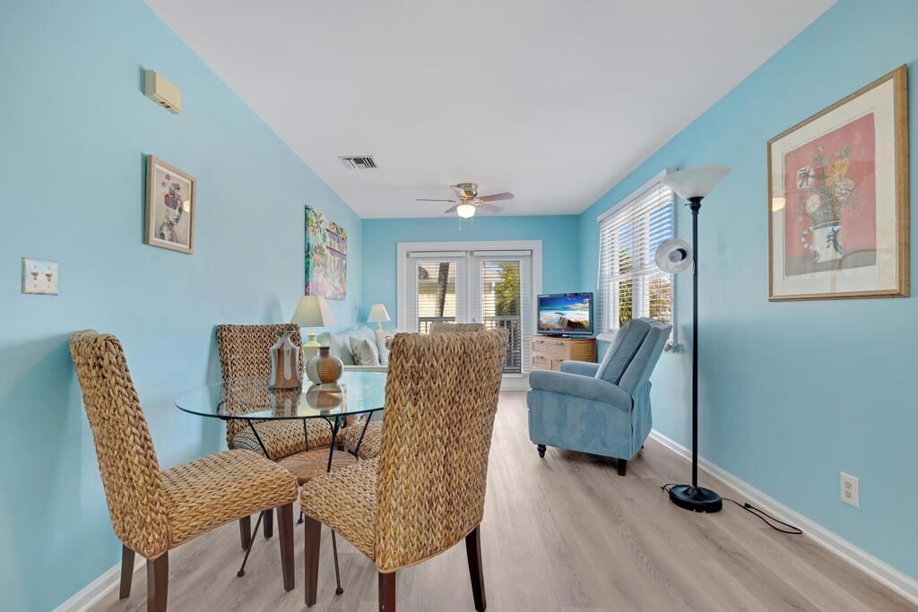 A living room with a glass coffee table, wicker chairs, a blue sofa, and a floor lamp.