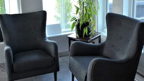 A room with two grey armchairs, a small table, and a potted plant. - Motel Quatre Saisons (Forestville)