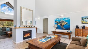 Ein geräumiges Wohnzimmer mit Kamin, einem großen Spiegel und einem Gemälde einer Schildkröte.