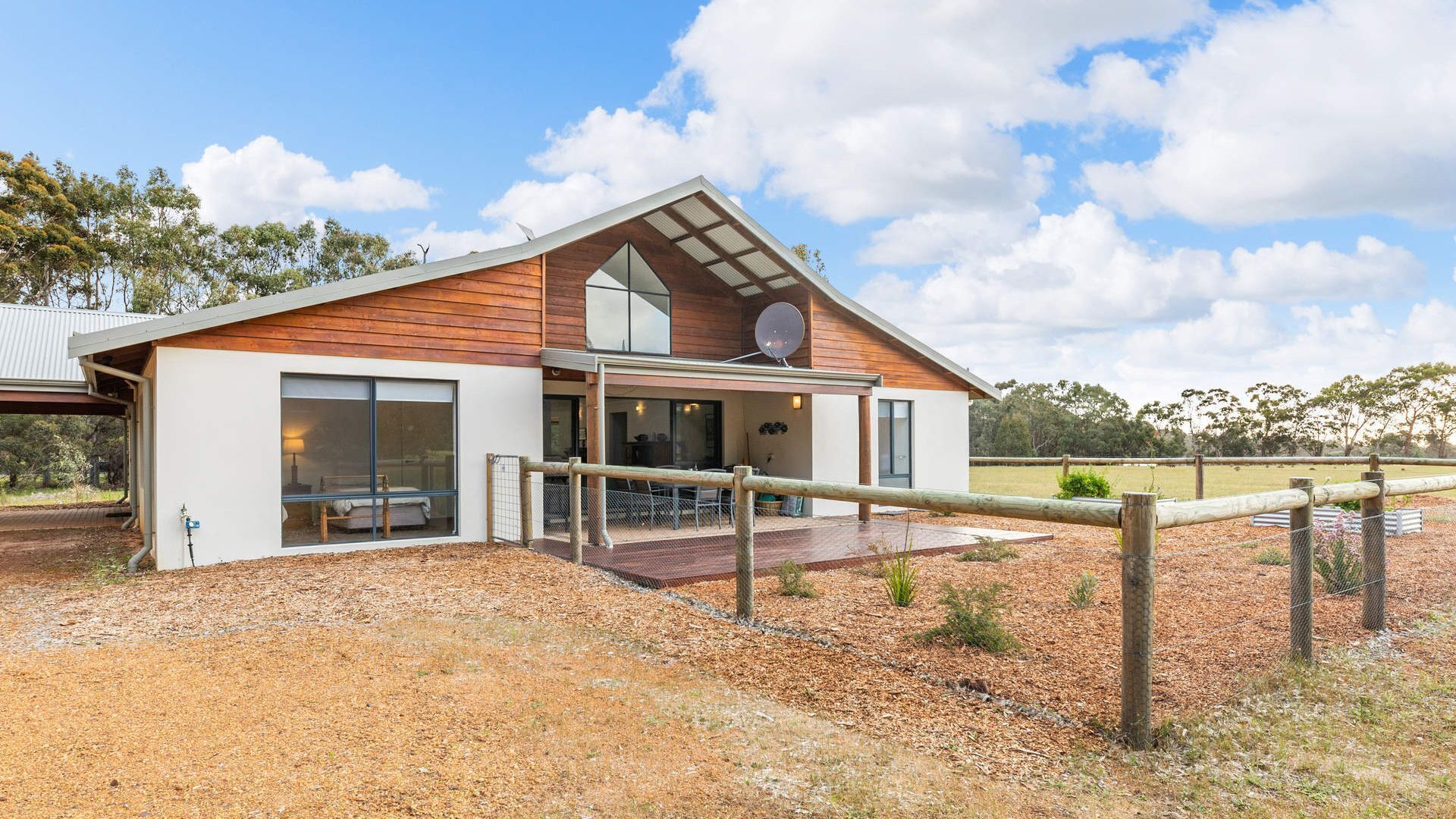A modern house with a large glass door, a covered patio, and a satellite dish.
