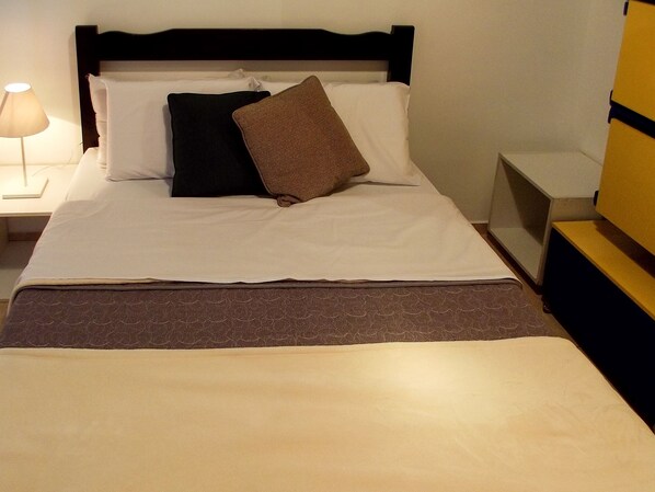 A neatly made bed with a dark headboard, white linens, and a brown throw blanket. - Studio de Casal no Brás  (Brás)