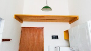 Ein Zimmer mit einem Holzregal, einer Tür, einem weißen Heizkörper und einem kleinen gerahmten Bild an der Wand.