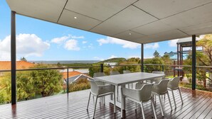 A covered outdoor dining area with a view of the sea and hills. - Beachside at Margaret River (Prevelly) - Modern beach house, ocean views, spacious interior, reverse (PREVELLY)