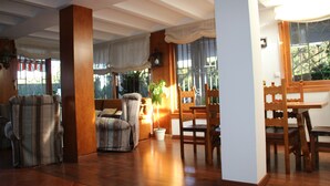 Amplia sala de estar con piso de madera, un sofá, una silla y una mesa de comedor con sillas.