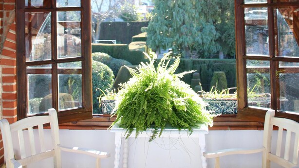 Una habitación con pared de ladrillo, un ventanal arqueado grande y un banco blanco.