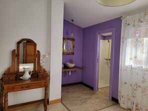 A bathroom with a wooden vanity, a mirror, a sink, and a shower area.