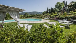 A pool area with lounge chairs and a pergola. - Romignano wine farm. Your villa in TUSCANY. (Traiana)