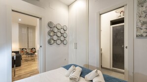 A hotel room with a bed, a wall-mounted mirror, a door, and a view of the adjacent room. - Modern Madrid Downtown Puerta Del Sol M (PRE2B) (Madrid)