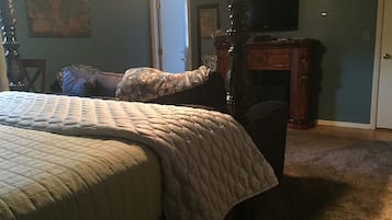 Un dormitorio con una cama grande, una mesita de noche de madera, un televisor y un mapa en la pared.