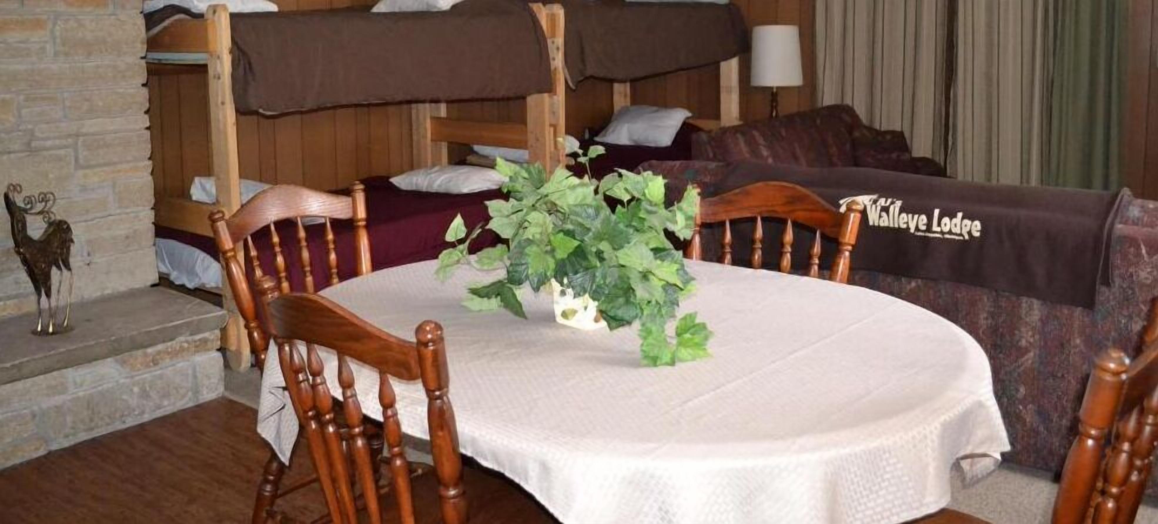 Una habitación acogedora con una mesa redonda, sillas de madera, un sofá y una cama con cabecero marrón.