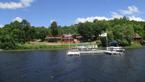 A lakeside property with a dock, a flag, and a building with a flagpole. - AJ's Lodge and Oven (Bergland)
