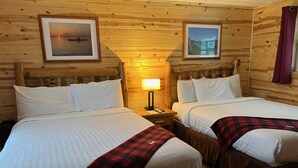 A room with two beds, wooden walls, and framed pictures. - AJ's Lodge and Oven (Bergland)