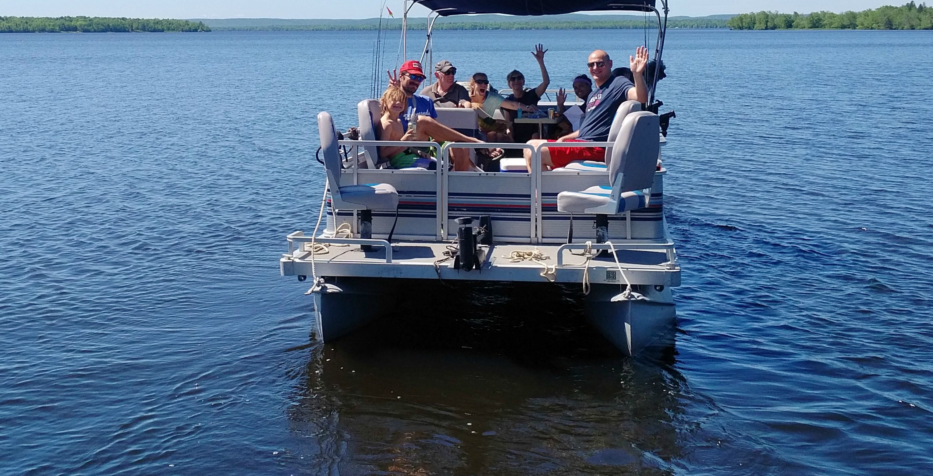 Un bateau rempli de passagers qui agitent les bras, équipé d’un auvent et de gilets de sauvetage.