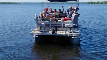 Un bateau rempli de passagers qui agitent les bras, équipé d’un auvent et de gilets de sauvetage.
