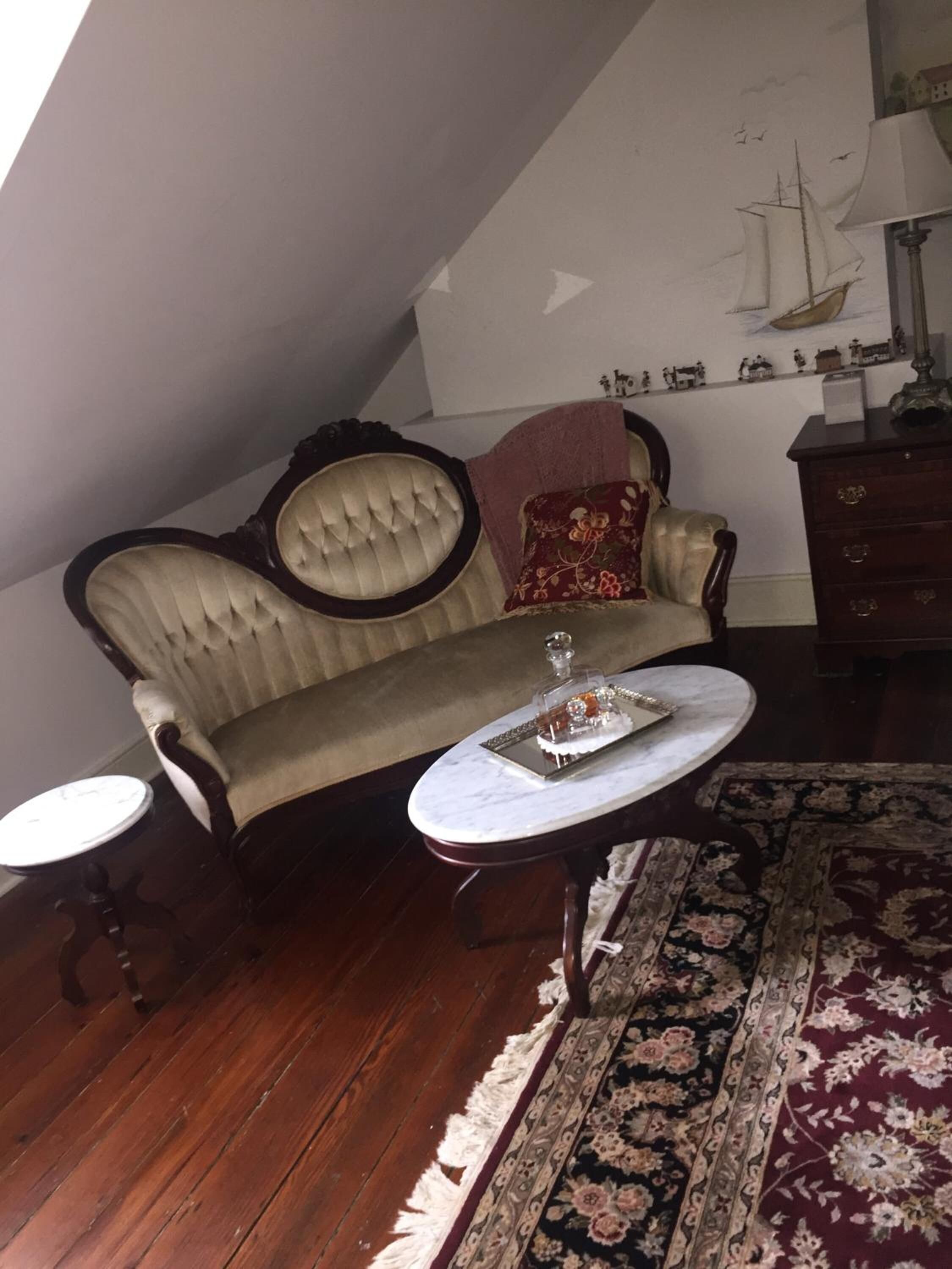 A cozy room with a sofa, a small table, a patterned rug, and a lamp.