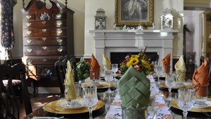 Un comedor formal con una larga mesa dispuesta para una comida, una chimenea y un grande aparador de madera.