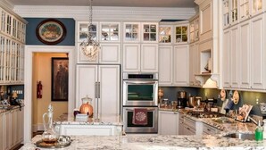 Una cocina amplia con armarios blancos, una isla central y electrodomésticos de acero inoxidable.