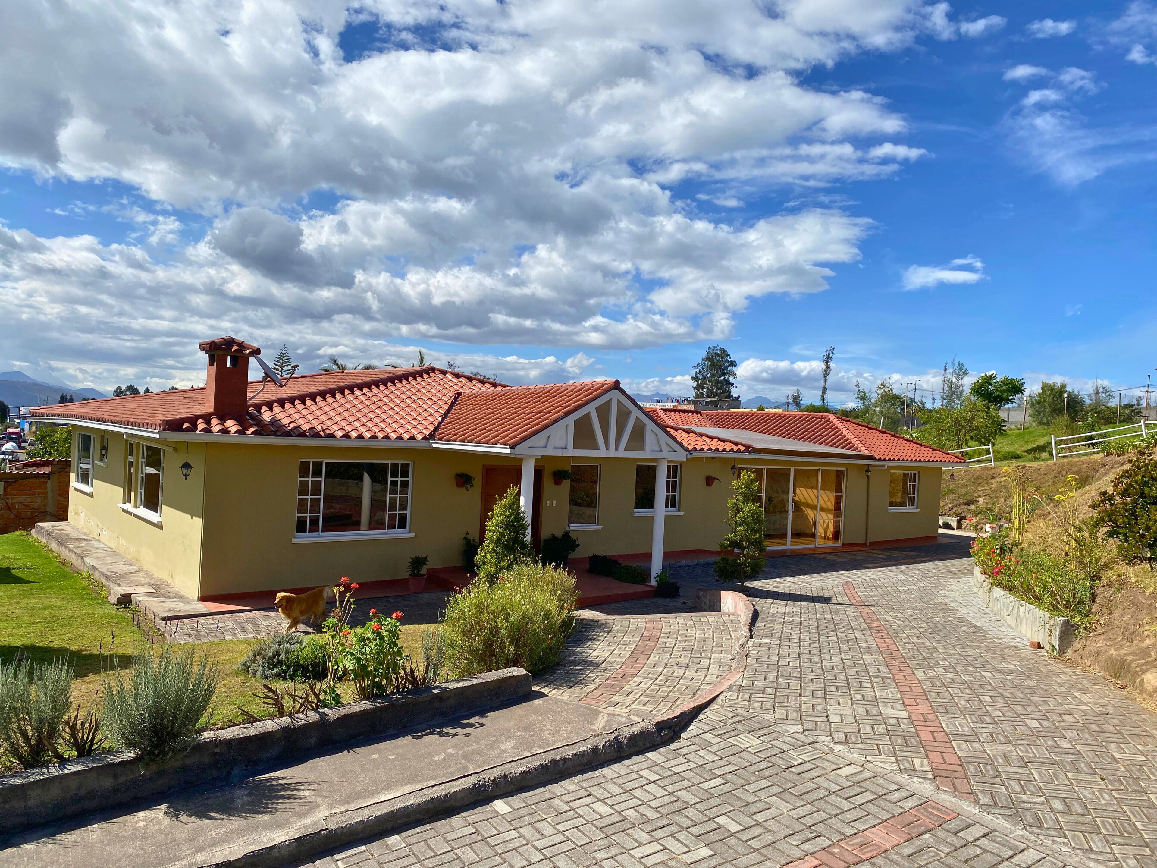 A two-story house with a red-tiled roof, a front porch, and a paved driveway leading to the entrance.