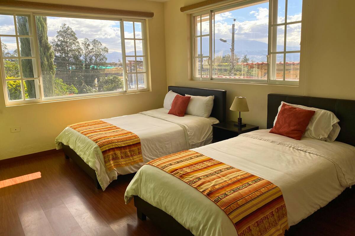 A hotel room with two beds, large windows, and a view of the cityscape.