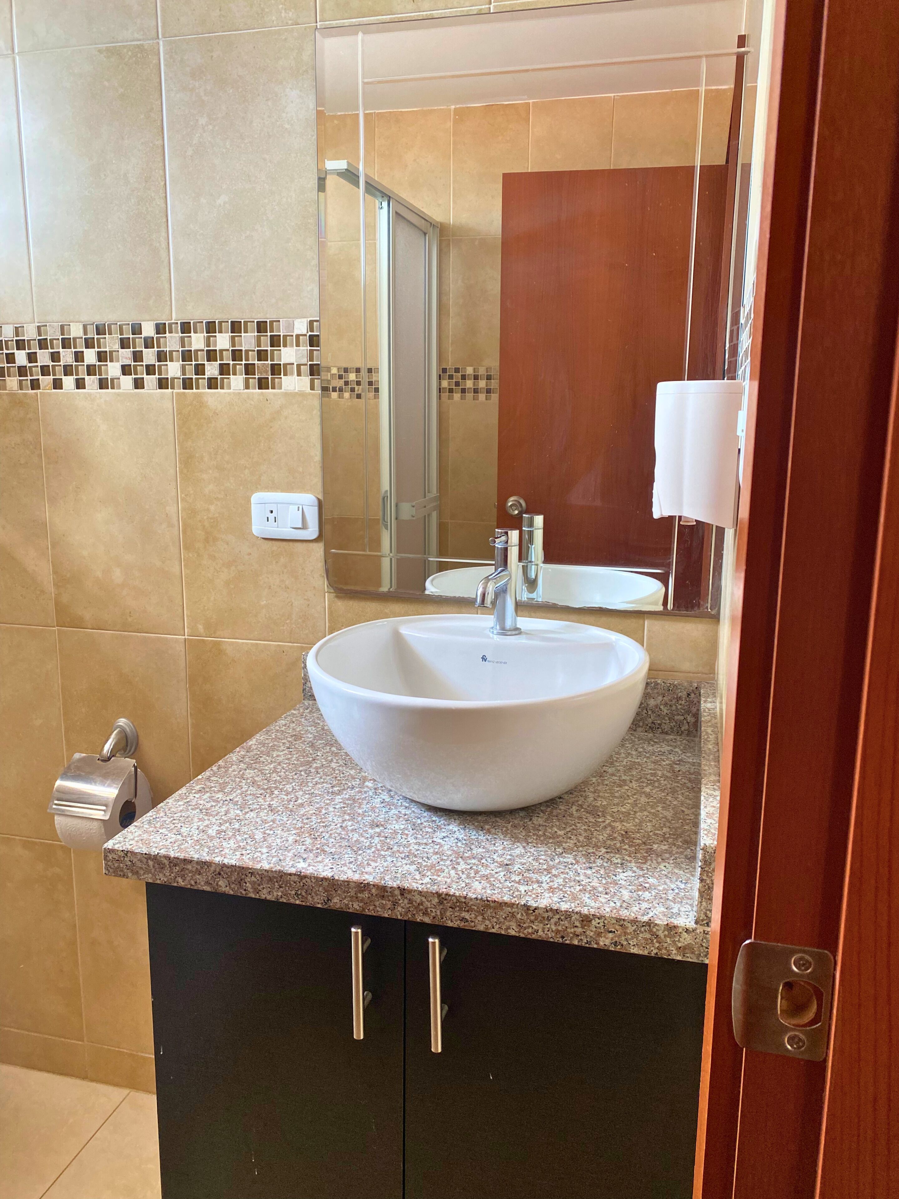 A bathroom with a white sink, a mirror, and a towel dispenser.