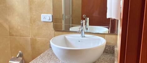 A bathroom with a white sink, a mirror, and a towel dispenser.