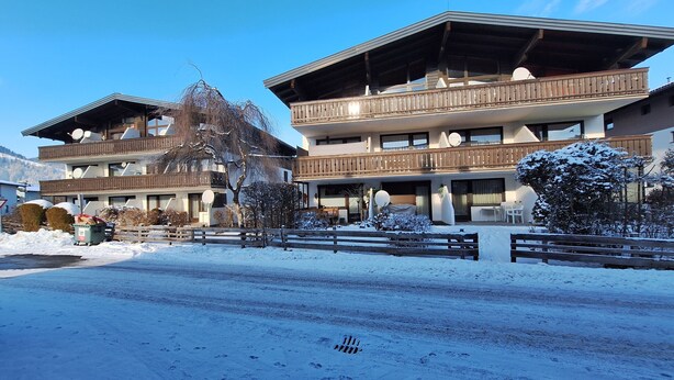 Ein mehrstöckiges Hotel mit Balkonen und einer Skipiste im Hintergrund.